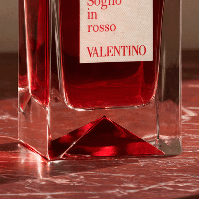 Ein eleganter, roter Duftflakon mit dem Etikett "Sogno in rosso" von Valentino, der auf einer marmorartigen Oberflache steht.